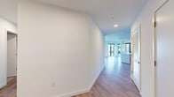 Located at 1991 Main Street in the heart of downtown Sarasota, Florida, this contemporary residence offers four bedrooms and three bathrooms across a thoughtfully designed single-floor layout. Light-toned hardwood flooring flows throughout, complementing the clean white walls and modern aesthetic found in every room. The open-concept kitchen and living area serves as the centerpiece of the home, featuring sleek gray cabinetry, stainless steel appliances including a full-size refrigerator and range, a neutral-toned countertop island, and floor-to-ceiling windows that flood the space with natural light and provide views of the surrounding Sarasota streetscape. The expansive living room continues the bright, airy feel with large black-framed windows that frame urban views. The generously sized primary bedroom includes access to well-organized closet space with built-in shelving systems. All three bathrooms showcase modern finishes, including large-format tile flooring, wood-toned vanities with undermount sinks, and frameless glass-enclosed showers. Additional closets provide ample storage throughout. A private balcony extends the living space outdoors, rounding out this polished and functional residence in one of Sarasota's most vibrant locations.