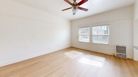 Located at 463 Hartford Ave in Los Angeles, CA, this one-bedroom, one-bathroom unit offers a compact and efficiently designed single-floor layout. Light wood flooring runs throughout, lending a clean and cohesive look to the space.

The spacious primary bedroom is the largest room in the unit, featuring bright white walls, a ceiling fan with light fixture, and a large window with blinds that invites natural light and offers outdoor views. A closet with mirrored sliding doors provides convenient storage.

The kitchen is thoughtfully arranged with warm honey-toned wood cabinetry, granite-style countertops, a gas range, a refrigerator, and a single-basin sink beneath a window fitted with blinds. Natural light filters in, making the kitchen feel open despite its efficient footprint.

The bathroom features a tiled shower and tub combination enclosed by a curved glass door. White marble-style tiles with a decorative mosaic accent border create a clean, polished aesthetic. The hallway connects the rooms, completing the straightforward and functional floor plan.

Overall, the unit offers a bright, clean living environment with practical finishes, making it a well-appointed space in the heart of Los Angeles.