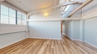 Located at 160 Lafayette Street in Jersey City, NJ, this two-bedroom, one-bathroom residence offers a well-designed layout with a bright, airy atmosphere throughout. The living room is a standout space, featuring striking architectural details including exposed beamed ceilings with white-painted wood planking, industrial-style ductwork, and warm light wood flooring that extends throughout the home. Large windows invite abundant natural light, enhancing the open and welcoming ambiance.

The galley-style kitchen is sleek and modern, appointed with flat-front cabinetry in soft gray and white tones, crisp white countertops, a stainless steel undermount sink, mosaic tile backsplash, and stainless steel appliances including a refrigerator and over-the-range microwave. A dedicated laundry area houses a stacked full-size washer and dryer for added convenience.

The two bedrooms are comfortably sized, with the primary bedroom offering ample space, light wood flooring, and natural light through a window with blinds. Four closets throughout provide generous storage.

The bathroom is cleanly finished with tile flooring, a tub-shower combination with mosaic tile surround, a navy blue vanity with white countertop, and a mirrored medicine cabinet. A hallway connects the rooms, completing this cohesive and functional layout.