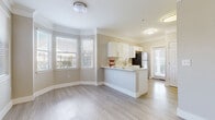 This single-story unit offers three bedrooms and one bathroom within a well-organized, efficiently designed floor plan. The open-concept kitchen and living area serves as the central hub of the space, featuring light wood-look flooring, crown molding, and neutral gray-toned walls that carry consistently throughout the unit. The kitchen is equipped with stainless steel appliances — including a refrigerator, electric range, and microwave — complemented by white shaker cabinetry and a light-colored countertop peninsula that provides additional workspace and separates the kitchen from the living area. A ceiling fan with lighting is installed in the living room, which also benefits from natural light through multiple windows.

The primary bedroom is a generously sized room with crown molding, a ceiling fan, and a dedicated walk-in closet fitted with wire shelving systems for organized storage. The two additional bedrooms are bright, moderately sized spaces, each accented with crown molding and the same wood-look flooring. The full bathroom features a tub-shower combination with tile surround. Clean finishes and a consistent design palette give the space a cohesive, move-in-ready appearance throughout.