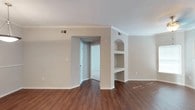 This single-floor residence offers a thoughtfully designed layout that balances comfort and functionality. The main living area showcases rich hardwood-style flooring and is highlighted by elegant crown molding and a distinctive architectural column featuring a built-in arched shelving unit — a standout design element that adds both character and practical storage. Natural light filters through window blinds and sliding glass doors with vertical blinds, contributing to the space's bright and airy atmosphere.

The kitchen is equipped with white cabinetry, white appliances including a refrigerator, microwave, and range, and features a curved breakfast bar that opens to the dining area. A pendant light fixture above the dining space adds a polished finishing touch.

The bedrooms are carpeted for comfort, each equipped with ceiling fan light fixtures and windows that allow natural light. One bedroom includes an en-suite bathroom and walk-in closet, while another features its own walk-in closet with built-in shelving. Two full bathrooms serve the residence, both finished with white vanities, large mirrors with multi-bulb lighting fixtures, and wood-style flooring. One bathroom includes a shower-tub combination. The overall aesthetic is clean, neutral, and move-in ready.