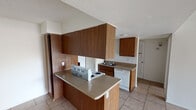 Located at 5830 N 67th Ave in Glendale, Arizona, this single-story home offers a straightforward and functional layout finished consistently with light beige tile flooring throughout. The kitchen is well-equipped, featuring warm wood-toned cabinetry that extends to the ceiling for generous storage, neutral laminate countertops, a white electric range, dishwasher, refrigerator, and a stainless steel double sink. A peninsula counter provides additional prep space and a natural division between the kitchen and adjoining areas. The living area is bright and open, illuminated by natural light streaming through a full sliding glass door fitted with vertical blinds, which also provides direct access to an outdoor patio. Textured ceilings are present throughout the home, lending a classic residential character. The bedrooms are comfortably sized, with white walls, tile flooring, and natural light from windows dressed with vertical blinds. At least one bedroom includes a closet with sliding doors offering built-in shelving. The overall layout, as visible in the dollhouse view, is compact yet efficiently organized, with clearly defined living, kitchen, and bedroom zones. This home presents a clean, move-in ready canvas in a convenient Glendale location.