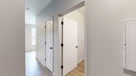 This well-appointed single-floor unit presents a cohesive modern aesthetic carried throughout every room. Light-toned wood-look luxury vinyl plank flooring runs continuously across the space, lending warmth and a sense of openness. The hallway connects multiple rooms via crisp white two-panel doors accented with matte black hardware, creating a clean contrast against the soft gray walls and white trim.

The kitchen is outfitted with rich dark-stained cabinetry, white countertops, a single-basin stainless steel sink with a brushed nickel faucet, and a full suite of stainless steel appliances including a refrigerator, electric range, built-in microwave, and dishwasher. The layout is efficient and functional, offering ample storage and prep space.

The bedrooms are bright and airy, benefiting from large windows dressed with horizontal blinds that allow for adjustable natural light. The rooms are generously proportioned and present a neutral palette ready for personalization. One bedroom features sliding glass door access, adding to its open feel.

The bathroom is finished with the same wood-look flooring and features a frameless glass-enclosed walk-in shower with chrome fixtures, a toilet, and a dark wood vanity with stone-look countertop. The overall ambiance of the unit is fresh, modern, and move-in ready.