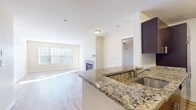 This contemporary 930 square foot apartment offers a thoughtfully designed living space with two bedrooms and two full bathrooms. The heart of the home is an open-concept living and dining area, highlighted by a sleek fireplace that serves as a focal point. Large windows flood the space with natural light, creating a bright and airy atmosphere.

The kitchen boasts modern amenities, including stainless steel appliances, granite countertops, and stylish dark wood cabinetry. A tile backsplash adds a touch of elegance. The primary bedroom, measuring 190 square feet, provides ample space and features plush carpeting for comfort. The second bedroom also offers carpeted flooring and a large window for natural illumination.

Both bathrooms are equipped with modern fixtures, including a vanity with storage, a toilet, and a shower/tub combination. The apartment features a mix of warm-toned wood-look flooring in the main living areas and soft carpeting in the bedrooms, creating a cohesive and inviting ambiance throughout. A central hallway connects all rooms, ensuring easy navigation of the space. The overall design emphasizes functionality and contemporary style, making it an ideal home for modern living.