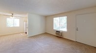 Located at 1539 Tavern Road in Alpine, California, this single-floor unit offers a clean, functional layout with a neutral color palette throughout. The living area is generously sized, featuring plush wall-to-wall carpeting, a textured ceiling, and a large window that invites abundant natural light and views of the surrounding greenery. A wall-mounted HVAC unit provides convenient climate control directly in the living space.

The kitchen is efficiently designed with white cabinetry, dark countertops, and wood-style flooring. It is equipped with a full suite of appliances including a refrigerator, electric range, dishwasher, and overhead ventilation. A window with blinds above the sink adds natural light to the space.

The bedrooms are well-proportioned with soft carpeting, textured ceilings, and bright windows. One bedroom features mirrored sliding closet doors that enhance the sense of space, along with a wall-mounted intercom panel. The rooms offer a quiet, versatile canvas for various furniture arrangements.

The unit includes two bathrooms. One features wood-style flooring, a single-sink vanity with white cabinetry, and a tub-shower combination. The second bathroom is similarly appointed with a tub-shower unit, a vanity with mirror, and neutral wall finishes. Both bathrooms maintain a clean, bright aesthetic throughout.