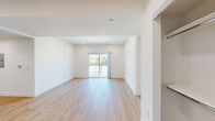This single-floor residence showcases a clean, contemporary design throughout, with light wood-tone flooring and crisp white walls creating a bright, airy atmosphere in every room. The open living area is generously proportioned, bathed in natural light from sliding glass doors that lead to a private balcony with outdoor views — an ideal setting for both relaxing and entertaining. Recessed lighting complements the natural light, enhancing the welcoming ambiance of the space.

The kitchen is thoughtfully designed with an abundance of white shaker-style cabinetry extending to the ceiling, offering substantial storage. Stainless steel appliances — including a gas range, microwave, and dishwasher — are paired with neutral-toned countertops, combining style and functionality seamlessly.

A well-connected hallway leads to the private areas of the residence. The bedrooms are comfortably sized, each featuring light-filled windows and the same warm wood-tone flooring found throughout. One bedroom enjoys direct balcony access via a sliding glass door. A spacious walk-in closet with built-in shelving and hanging rods provides excellent organization potential.

Both bathrooms feature a consistent, modern aesthetic with white cabinetry, neutral countertops, tub-and-shower combinations enclosed by sliding glass doors, and wood-tone flooring, maintaining a cohesive and polished look across the entire residence.
