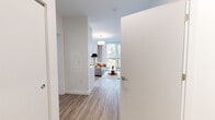 Located at 11 E Pleasant St in Amherst, MA, this thoughtfully designed 2-bedroom, 1-bathroom unit offers a clean, modern aesthetic across a single floor. The open-concept living and dining area is filled with natural light from floor-to-ceiling windows and sliding glass doors that lead to a private balcony with outdoor views. Wood-look flooring runs throughout the main living spaces, complementing the bright white walls and contemporary design.

The kitchen features sleek white cabinetry, light countertops, stainless steel appliances including a built-in microwave and French door refrigerator, and a glass-top range — creating a functional and stylish cooking space.

The primary bedroom is generously proportioned, offering large windows with scenic outdoor views, a wall-mounted mini-split HVAC unit, and a built-in closet with sliding doors. A dedicated walk-in closet provides ample storage with adjustable shelving and hanging rods. The second bedroom also includes its own mini-split unit and closet space. The full bathroom is finished with wood-look flooring, clean white walls, and a shower-tub combination. Each room reflects a cohesive, minimalist design with an emphasis on comfort and functionality.