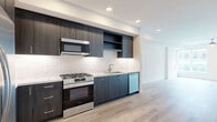 Located in the heart of San Diego's vibrant downtown at 1509 Broadway, this modern one-bedroom, one-bathroom residence offers a thoughtfully designed open-concept layout. Light wood-toned flooring flows throughout, lending warmth and continuity across every room.

The kitchen is a standout feature, showcasing dark espresso cabinetry reaching to the ceiling, a classic white subway tile backsplash, stone-look countertops, and a full suite of stainless steel appliances including a gas range, over-the-range microwave, dishwasher, and a large side-by-side refrigerator. Recessed lighting illuminates the space cleanly.

The open living area is bright and airy, anchored by expansive floor-to-ceiling windows that invite an abundance of natural light and offer views of the surrounding cityscape. A ceiling fan adds both function and style to the space.

The bedroom is comfortably sized, featuring a large window with urban views, a ceiling fan, and crisp white walls. A dedicated closet provides convenient storage.

The bathroom is elegantly appointed with large-format tile flooring, a fully glass-enclosed walk-in shower clad in natural stone-look tile, and a wall-mounted vanity cabinet for additional storage. Clean lines and neutral tones complete the refined aesthetic throughout this well-appointed San Diego residence.