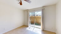 This efficient single-story, one-bedroom, one-bathroom home offers a well-organized layout across a single floor, encompassing a combined kitchen and living area, a dedicated bedroom, a full bathroom, and a hallway connecting the spaces. Light-toned ceramic tile flooring runs consistently throughout the entire home, contributing to a clean, cohesive aesthetic.

The living area is bright and airy, benefiting from a ceiling fan and a full-width sliding glass door that opens to a private, fenced outdoor patio. Natural light pours through the glass, creating a welcoming atmosphere. A passage from the living area leads directly into the kitchen, which features white cabinetry, tile backsplash, and black appliances including a refrigerator and range.

The bedroom is a comfortable size, equipped with its own ceiling fan, a large window fitted with blinds that allow ample natural light, and a six-panel door providing privacy. The full bathroom includes a single-sink white vanity with a speckled countertop, white cabinetry, a wall-mounted mirror with overhead lighting, and a shower-tub combination. A hallway connects the main rooms, completing the practical and straightforward floor plan of this single-level home.