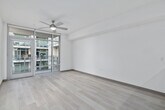 This well-designed 2-bedroom, 1-bathroom residence offers a thoughtful single-floor layout with a clean, contemporary aesthetic throughout. The open-concept kitchen and living area form the heart of the unit, where light wood-toned flooring, white walls, and a ceiling fan create a bright, airy atmosphere. The kitchen is appointed with textured dark-wood cabinetry, a light green glass tile backsplash, white quartz countertops, a peninsula island with pendant globe lighting, and a full suite of stainless steel appliances including a refrigerator, electric range, microwave, and dishwasher. The living room extends naturally from the kitchen, benefiting from floor-to-ceiling sliding glass doors that open to a balcony and flood the space with natural light. Both bedrooms are carpeted and include ceiling fans and windows with outdoor views. The primary bedroom features its own access and a dedicated closet. The hallway connects the private areas of the unit efficiently. The bathroom is accessed via louvered doors and features large-format tile flooring, a wood-grain vanity with white countertop, a wall mirror, and a clean, neutral finish throughout. A separate closet provides additional storage. The unit presents a cohesive modern design with practical, well-distributed living spaces.