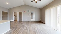 Located at 3276 Jim St in Rapid City, South Dakota, this well-designed single-story home offers a thoughtful layout across two bedrooms, one bathroom, and a combined kitchen and living area. The open-concept kitchen and living room is immediately impressive, highlighted by soaring vaulted ceilings with a ceiling fan, light-toned luxury vinyl plank flooring, and a neutral gray color palette. The kitchen features white shaker-style cabinetry, a light quartz countertop with a peninsula and built-in sink, black appliances including a range and refrigerator, and stylish pendant lighting. The spacious living area flows seamlessly from the kitchen, with in-unit laundry access visible nearby. The primary bedroom is generously sized and includes vaulted ceilings, large sliding glass doors with vertical blinds allowing abundant natural light, and vinyl plank flooring. The second bedroom offers plush carpeting, a window with neighborhood views, and a dedicated closet with a wood-toned door. The full bathroom is finished with a white vanity, quartz-style countertop, large mirror, and wood-look flooring. Each room reflects a clean, contemporary aesthetic designed for comfort and functionality.