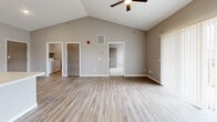Located at 3276 Jim St in Rapid City, South Dakota, this well-designed single-story home offers a thoughtful layout across two bedrooms, one bathroom, and a combined kitchen and living area. The open-concept kitchen and living room is immediately impressive, highlighted by soaring vaulted ceilings with a ceiling fan, light-toned luxury vinyl plank flooring, and a neutral gray color palette. The kitchen features white shaker-style cabinetry, a light quartz countertop with a peninsula and built-in sink, black appliances including a range and refrigerator, and stylish pendant lighting. The spacious living area flows seamlessly from the kitchen, with in-unit laundry access visible nearby. The primary bedroom is generously sized and includes vaulted ceilings, large sliding glass doors with vertical blinds allowing abundant natural light, and vinyl plank flooring. The second bedroom offers plush carpeting, a window with neighborhood views, and a dedicated closet with a wood-toned door. The full bathroom is finished with a white vanity, quartz-style countertop, large mirror, and wood-look flooring. Each room reflects a clean, contemporary aesthetic designed for comfort and functionality.