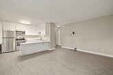 This compact yet functional 3-bedroom, 1-bathroom single-floor unit is thoughtfully designed to make the most of its available space. The kitchen stands out as a highlight, featuring crisp white shaker-style cabinetry, granite-look countertops, stainless steel appliances including a refrigerator, electric range, and built-in microwave, as well as a peninsula that provides additional prep and counter space. Light wood-look flooring adds warmth and continuity throughout the kitchen area.

The living room is an open, neutral-toned space with light vinyl plank flooring, a textured ceiling, and a window fitted with vertical blinds that allows natural light to filter in. A wall-mounted HVAC unit provides climate control.

Each of the three bedrooms features the same durable vinyl plank flooring and neutral wall tones, creating a clean and versatile canvas. Windows with vertical blinds bring in natural light, and sliding-door closets with built-in shelving and hanging rods offer practical storage. One bedroom also features additional shelving for added organization.

The bathroom is clean and straightforward, equipped with a full tub-shower combo with brushed nickel fixtures and granite-look countertop accents. Textured ceilings are consistent throughout the unit, contributing to a cohesive residential aesthetic.