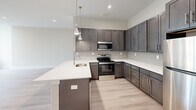 Located at 70 Church St in Flemington, NJ, this well-appointed one-bedroom, one-bathroom unit offers a thoughtfully designed single-floor layout with generous living space. Light wood-style flooring flows throughout, complementing the clean, neutral palette that gives the home a bright and airy feel.

The open-concept kitchen and living area serves as the heart of the unit. The kitchen is outfitted with rich dark-toned shaker cabinetry, quartz countertops, stainless steel appliances, and a peninsula with a built-in sink — all illuminated by stylish pendant lighting. The adjacent living area is expansive, featuring large windows that draw in abundant natural light and offer views of the surrounding neighborhood, along with a wall-mounted split HVAC unit for year-round comfort.

The bedroom is a comfortable retreat, complete with a double-door closet and a wall-mounted HVAC unit. With four closets total throughout the unit, storage is plentiful. The bathroom features a full tub-shower combo finished with white subway-style tile and sleek matte black fixtures. A dedicated laundry area and a well-proportioned hallway round out this efficiently planned home, making it an ideal space for modern everyday living.