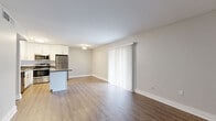 Located at 4350 W Kennedy Blvd in Tampa, FL, this two-bedroom, one-bathroom unit offers a practical and modern layout across a single floor. The open-concept living and kitchen area forms the heart of the home, featuring warm wood-style flooring that extends throughout the space. The kitchen is well-appointed with crisp white shaker cabinetry, a subway tile backsplash, dark countertops, a central island, and a full suite of stainless steel appliances including a refrigerator, range, microwave, and dishwasher. The living area is bright and open, with a large sliding glass door dressed in vertical blinds that allows natural light to fill the room. The primary bedroom is generously sized and includes access to a dedicated walk-in closet outfitted with double hanging rods, providing ample storage. The second bedroom features a large sliding panel closet. The bathroom is finished with white tile surrounding a full soaking tub and shower combo with chrome fixtures. Neutral gray walls, clean white trim, and consistent flooring throughout lend a cohesive, move-in-ready aesthetic to the entire unit.