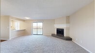 Located at 8100 Perry St in Overland Park, Kansas, this well-appointed two-bedroom, two-bathroom residence offers a thoughtfully designed single-floor layout. The open-concept living and dining area serves as the heart of the home, highlighted by a striking corner brick fireplace with a white mantel and plush carpeting throughout. A sliding glass door leads to a private balcony, filling the space with natural light and offering outdoor views. The kitchen is efficiently designed with stainless steel appliances, including a refrigerator, range, and microwave, complemented by white cabinetry, a breakfast bar, and durable hardwood-style flooring. A skylight adds additional brightness to this functional space. The spacious primary bedroom features a ceiling fan, a dedicated closet, and natural light from a window with blinds. The en-suite bathroom includes a wide vanity with white cabinetry and a clean countertop. The second bedroom also includes a ceiling fan and natural light. The second bathroom mirrors the same clean, neutral aesthetic. Additional conveniences include four closets, in-unit laundry, a utility room, and a hallway providing practical storage and connectivity throughout the residence.