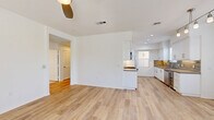 Located at 5040 Camino San Fermin in the desirable Carmel Valley neighborhood of San Diego, this thoughtfully designed single-story home offers three bedrooms and two bathrooms within a well-organized, comfortable floor plan. The open-concept living and dining area is anchored by a tile-surround fireplace and ceiling fan, creating a warm yet airy atmosphere. Light wood-look flooring flows throughout the main living spaces, while large windows invite abundant natural light throughout the day. The kitchen features crisp white shaker cabinetry, a decorative tile backsplash in warm earth tones, quartz countertops, stainless steel appliances including a wine cooler, and a peninsula that seamlessly connects to the living area. The generously sized primary bedroom includes its own ceiling fan, direct balcony access, and a spacious walk-in closet with built-in shelving. Secondary bedrooms are finished with plush carpet and include closets and natural light. The bathrooms are tastefully appointed, with one featuring a soaking tub with tile surround accented by a mosaic tile border. A dedicated laundry room houses a full-size washer and dryer. An attached garage and six closets throughout provide exceptional storage. The home's clean, contemporary aesthetic and practical layout make it an ideal residence in one of San Diego's premier communities.