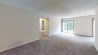Located at 542 S Broadway in Pennsville, NJ, this single-floor unit offers a clean, functional layout designed for comfortable everyday living. The galley-style kitchen is a standout feature, outfitted with crisp white shaker cabinetry, light marble-look countertops, a stainless undermount sink, and black appliances including a range, refrigerator, and dishwasher. Durable wood-look flooring runs throughout the kitchen, while a ceiling fan and sliding glass door at the far end of the adjoining area invite natural light and outdoor views. The open living area is generously proportioned, finished with neutral wall-to-wall carpeting and a textured ceiling. A sliding glass door leads to an outdoor space, further brightening the room. The bedrooms are well-sized, each featuring plush carpeting and windows with serene greenery views. One bedroom includes a double sliding-door closet for ample storage. The bathroom is thoughtfully finished with large white subway tiles lining the tub surround, accented by a decorative mosaic tile border near the top, and complemented by chrome fixtures. Throughout the space, a neutral color palette and abundant natural light create a bright, welcoming atmosphere.