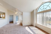 Located at 7921 W Mansfield Pkwy in Lakewood, Colorado, this single-story, 2-bedroom, 2-bathroom home offers a well-designed, efficient layout. The living room immediately impresses with its vaulted ceiling, a ceiling fan, and a striking arched window that floods the space with natural light. Plush carpeting extends throughout the main living and bedroom areas, creating a warm, comfortable atmosphere.

The kitchen is open-concept and features a peninsula with a built-in sink and dishwasher, wood-toned lower cabinetry with white upper cabinets, a white electric range, a refrigerator, and a built-in microwave. Hardwood-style flooring runs through the kitchen, providing a clean contrast to the carpeted areas. The kitchen opens directly toward the living room, making the space feel connected and airy.

The primary bedroom is generously sized and includes access to a walk-in closet as well as its own bathroom. The second bedroom features a window with exterior views and is conveniently positioned near the second full bathroom. Both bathrooms include tub/shower combinations with tile surrounds, single-sink vanities with wood-accented cabinetry, and hardwood-style flooring. An in-unit laundry area adds everyday convenience to this well-rounded home.