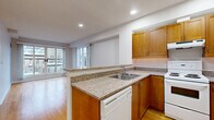 Located at 20 York St in the heart of Ottawa, this 2-bedroom, 1-bathroom residence offers a well-organized single-floor layout designed for comfortable urban living. The entryway features warm hardwood flooring and recessed lighting, providing a clean and welcoming transition into the home. The combined kitchen and living room area serves as the central hub of the space. The kitchen is outfitted with warm-toned wood cabinetry, granite-look countertops, a double sink, and white appliances including a dishwasher, electric range, and refrigerator, all set on hardwood floors. The living area flows naturally from the kitchen and is bathed in natural light from large sliding glass doors that open to a balcony, offering views of Ottawa's surrounding urban architecture. The primary bedroom is a generously sized retreat with large multi-pane windows that frame city views and allow abundant natural light, finished with soft carpet flooring. The second bedroom is equally comfortable, also carpeted with neutral tones. The bathroom features tile flooring, a full soaker tub with a tile surround, and a handheld showerhead. A hallway connects all rooms efficiently, completing this practical and well-appointed urban residence.