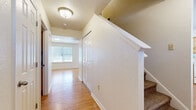 This well-appointed two-story home at 5107 Leonard Ave in Fort Riley, Kansas, offers three bedrooms and two bathrooms across a thoughtfully designed layout. The main floor features a bright, open living room with hardwood-style flooring, a sliding glass door leading to a private outdoor patio, and abundant natural light from multiple windows. The kitchen flows seamlessly from the living area and is equipped with warm wood cabinetry, ample counter space, and hardwood-style flooring throughout. A dedicated laundry room with overhead cabinetry and a utility counter adds everyday convenience on the main level. Upstairs, the upper floor provides generous living space, including a spacious primary bedroom with a ceiling fan and its own walk-in closet featuring wire shelving on multiple walls for organized storage. Two additional carpeted bedrooms each include windows for natural light. The full shared bathroom upstairs is equipped with a double-sink vanity, tile flooring, and a tub-shower combination. A carpeted staircase with a clean white railing connects the two floors, and a hallway with hardwood-style flooring ties the upper level together. This home offers a practical and comfortable layout suited for a variety of living arrangements.
