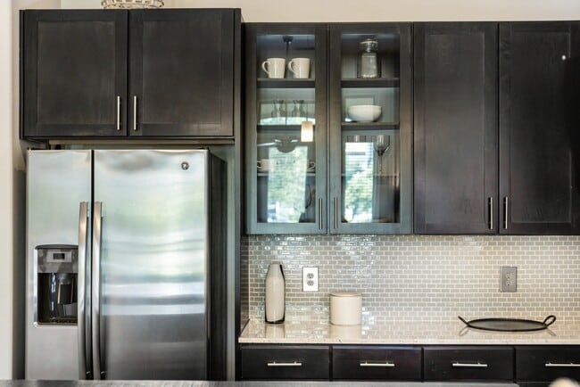 Cocina con gabinetes color espresso, encimeras de granito, placa para salpicaduras de azulejos y electrodomésticos de acero inoxidable. - Avalon Lakeside