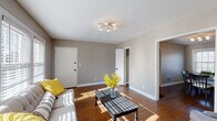 Located at 2315 Glenmary Ave in Louisville, Kentucky, this single-story home offers a cohesive and well-designed layout with warm neutral tones and rich hardwood flooring carried throughout. The inviting living room is bathed in natural light from large windows with plantation shutters and features a contemporary sputnik-style ceiling fixture, creating a bright and welcoming atmosphere. Adjacent to the living area, a dedicated dining space accommodates a full dining set beneath a matching light fixture, with dual windows providing additional natural light. The kitchen is outfitted with white shaker-style cabinetry, granite countertops, a subway tile backsplash, matte black hardware, and a classic black-and-white checkered floor, complemented by a stacked washer and dryer unit integrated into the space. The home includes multiple bedrooms, each featuring hardwood floors, neutral walls, ample natural light from well-placed windows, and closet access. The bathroom presents a clean, classic aesthetic with full subway tile surrounding the tub-shower combination, navy accent tile, and matte black fixtures. Throughout, the home maintains a consistent, polished character defined by thoughtful finishes and an abundance of natural light.