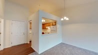 This well-appointed 1-bedroom, 1-bathroom residence offers a thoughtfully designed single-level layout. The open living and dining area is generously proportioned, featuring plush wall-to-wall carpeting, elegant chandelier lighting, and a large sliding glass door dressed with vertical blinds that floods the space with natural light and provides access to the outdoors. A pass-through window connects the living area to the kitchen, creating an open and connected feel. The kitchen is equipped with warm honey-toned oak cabinetry extending to the ceiling for ample storage, white appliances including a refrigerator, electric range, and dishwasher, along with a double sink and light countertops, all set over durable hardwood-style flooring. The bedroom is a comfortable retreat with soft carpeting, a ceiling fan, and a window overlooking greenery. It includes access to a closet and connects conveniently to the bathroom, which features tile flooring, a bathtub with shower, and a toilet. A dedicated entryway with hardwood-style flooring completes the layout. Throughout the residence, a neutral color palette and clean lines create a bright, welcoming ambiance.
