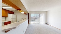 Located at 12726 N MacArthur Blvd in Oklahoma City, Oklahoma, this two-bedroom, two-bathroom residence offers a practical and well-organized single-floor layout. The open-concept living and dining area is finished with plush carpet and anchored by a large sliding glass door dressed in vertical blinds, flooding the space with natural light and providing a view of the surrounding exterior. A textured ceiling adds a classic touch throughout the main living area.

The kitchen is designed with a pass-through bar that connects seamlessly to the living space, promoting an open and social feel. Warm oak cabinetry lines both the upper and lower sections, complemented by white appliances including a refrigerator, range, and microwave. The layout is efficient and practical for everyday use.

The primary bedroom is a comfortable size, featuring carpet flooring, a natural light-admitting window with blinds, and a sliding-door closet offering ample storage. The primary bathroom is well-appointed with a dual-sink vanity featuring oak cabinetry, a large mirror, and a bathtub, all set on wood-look vinyl plank flooring. The second bathroom is equally functional, with a single vanity and similar finishes. Warm wood trim and oak-toned doors carry a consistent design language throughout the entire residence.