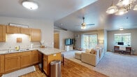 This single-floor residence offers a thoughtfully designed open-concept layout that seamlessly connects the kitchen and living areas. The kitchen is equipped with warm honey-toned cabinetry, granite-style countertops, black appliances including a refrigerator, electric range, microwave, and dishwasher, and a double-basin sink. A peninsula counter with bar seating provides a natural transition into the living space, where hardwood-style flooring extends throughout. The living room is bright and spacious, featuring a ceiling fan with light fixture and sliding glass doors that open to a private balcony overlooking lush greenery. A flexible secondary space adjacent to the living area is well-lit by multiple windows and carpeted, making it suitable as a home office or additional lounge area. The bedroom is comfortably sized, carpeted, and features a ceiling fan, a window with natural light, and baseboard heating. An additional vanity area with ample counter space is accessible near the bedroom. The bathroom includes a single-sink vanity with wood cabinetry, a large mirror, tile flooring, and a shower-tub combination. Throughout the residence, neutral tones and consistent finishes create a cohesive and functional living environment.
