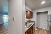 This single-floor, 2-bedroom, 2-bathroom residence offers a thoughtfully designed layout that maximizes functionality and comfort. The open-concept living and kitchen area serves as the heart of the home, featuring warm hardwood-style flooring, a ceiling fan, and a sliding glass door that fills the space with natural light while offering views of a lush green outdoor area. A baseboard heating system runs along the living room wall, ensuring year-round comfort.

The kitchen is well-equipped with rich walnut-toned cabinetry, granite-style countertops, stainless steel appliances including a refrigerator, gas range, and microwave, as well as a double basin sink. A pass-through counter connects the kitchen to the living area, enhancing the open feel. An adjacent closet provides convenient pantry or storage space.

Both bedrooms are carpeted and feature neutral tones, with the second bedroom benefiting from a window that brings in natural light and outdoor views. Each bedroom includes its own closet for ample storage.

The two bathrooms are clean and functional, each featuring warm wood vanities, white countertops, large mirrors with overhead lighting, and tiled tub-shower combinations. The overall design is practical and cohesive, with a neutral color palette throughout.