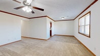 Located at 2460 Clearwater Ct in Bowling Green, Kentucky, this single-story, 3-bedroom, 2-bathroom home offers a practical and comfortable layout throughout. Warm wood trim and baseboards are consistent across every room, lending a cohesive, classic character to the interior. The living room features plush carpeting, a ceiling fan with light fixture, and natural light from a window, creating a welcoming common area. The kitchen is equipped with rich oak cabinetry, light granite-style countertops, a double stainless steel sink, a window above the counter, and tile flooring — with space for a refrigerator and dishwasher. The generously sized primary bedroom showcases crown molding, a ceiling fan, and a transition from carpet to tile that connects to a private en-suite bathroom. Additional bedrooms are carpeted and include ceiling fans and windows that bring in natural light. The bathrooms feature oak vanities with solid countertops and tile flooring. A dedicated laundry room provides overhead cabinetry, washer and dryer hookups, and tile flooring. The attached garage offers additional utility space with interior access. Throughout the home, neutral wall tones and consistent wood accents create a clean, move-in ready atmosphere.