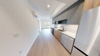 This contemporary 810-square-foot apartment at 16771 Redmond Way in Redmond, WA, offers a well-designed single-floor layout with 2 bedrooms and 1 bathroom. Light wood-tone flooring flows throughout the unit, complementing the clean white walls and modern aesthetic. The open living area connects seamlessly to a compact kitchen featuring warm wood cabinetry, subway tile backsplash, a stainless steel sink, and black stainless appliances including a built-in microwave, range, and refrigerator. Sliding glass doors open from the living area onto a private balcony with iron railings, offering views of surrounding greenery. The primary bedroom measures 110 square feet and includes a dedicated walk-in closet with dual chrome hanging rods and built-in shelving. The second bedroom is bright and well-proportioned, featuring a large window with natural light and its own closet with a chrome rod. The full bathroom is outfitted with a wood-grain vanity, white quartz countertop, an under-mount sink with matte black fixtures, and a backlit LED vanity mirror. A dedicated laundry room adds everyday convenience. The hallway connects all rooms efficiently, completing this thoughtfully laid-out modern residence.