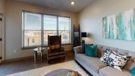 This single-floor residence offers a thoughtfully designed layout that integrates living, dining, kitchen, bedroom, and bathroom spaces in a cohesive flow. The open-concept living area features light wood-tone flooring, recessed lighting, and large windows fitted with horizontal blinds that allow ample natural light while framing outdoor views. Seating includes a tufted gray sofa and a classic wingback chair, complemented by eclectic décor in teal and gold tones.

The kitchen is well-equipped with rich dark-wood cabinetry, dark granite countertops, stainless steel appliances including a range and built-in microwave, and a herringbone-patterned tile backsplash. A breakfast bar with pendant lighting and bar seating connects the kitchen to the living area, reinforcing the open layout.

The bedroom accommodates a queen-sized bed and includes a double-door closet for ample storage. Warm, neutral wall tones and bedside lamps create a calm atmosphere, while a window provides natural light and outdoor balcony access.

The bathroom features a dark-wood vanity with granite countertops, a large framed mirror, a shower-tub combo, light tile flooring, and clean white walls, offering a functional yet refined aesthetic throughout.