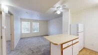 Located at 301 El Pueblo Rd NW in Los Ranchos de Albuquerque, New Mexico, this single-floor, one-bedroom, one-bathroom unit offers a practical and well-organized layout. The open-concept living, dining, and kitchen area forms the heart of the home, with plush carpeting in the living space and a ceiling fan providing year-round comfort. Natural light filters in through dual windows, creating a bright and welcoming atmosphere. The kitchen is efficiently designed with light wood-look flooring, white cabinetry with wood-tone accents, a full suite of white appliances including a refrigerator, electric range, and dishwasher, and a peninsula counter that separates the kitchen from the living and dining areas. The bedroom features soft carpeting, a ceiling fan, and a window with views to the outdoors, offering a quiet and comfortable retreat. Two closets provide ample storage throughout the unit. The bathroom is clean and functional, featuring a tub/shower combination with safety grab bars and wood-look flooring. An in-unit laundry area adds everyday convenience. Overall, the space presents a tidy, functional layout suited for efficient single-occupant or couple living.