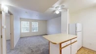 Located at 301 El Pueblo Rd NW in Los Ranchos de Albuquerque, New Mexico, this single-floor, one-bedroom, one-bathroom unit offers a practical and well-organized layout. The open-concept living, dining, and kitchen area forms the heart of the home, with plush carpeting in the living space and a ceiling fan providing year-round comfort. Natural light filters in through dual windows, creating a bright and welcoming atmosphere. The kitchen is efficiently designed with light wood-look flooring, white cabinetry with wood-tone accents, a full suite of white appliances including a refrigerator, electric range, and dishwasher, and a peninsula counter that separates the kitchen from the living and dining areas. The bedroom features soft carpeting, a ceiling fan, and a window with views to the outdoors, offering a quiet and comfortable retreat. Two closets provide ample storage throughout the unit. The bathroom is clean and functional, featuring a tub/shower combination with safety grab bars and wood-look flooring. An in-unit laundry area adds everyday convenience. Overall, the space presents a tidy, functional layout suited for efficient single-occupant or couple living.