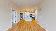 This 680-square-foot, single-floor unit at 1211 Carrington Blvd in Mount Pleasant, WI offers a well-designed 1-bedroom, 1-bathroom layout with modern finishes throughout. The open-concept kitchen and living area serves as the heart of the home, featuring a central island with pendant lighting, white upper shaker cabinets, gray lower cabinets with black hardware, quartz countertops, stainless steel appliances, and light hardwood flooring. A stacked washer and dryer is conveniently integrated into the kitchen area. The living space benefits from large windows that bring in natural light and offer outdoor views. The 140-square-foot bedroom is carpeted and includes a generously sized walk-in closet with wire shelving. The bathroom is finished with gray shaker-style cabinetry, a white quartz vanity top, an undermount sink, brushed nickel faucet, black hardware accents, and hardwood-style flooring. Neutral wall tones and clean white trim are consistent throughout the unit, creating a cohesive and contemporary aesthetic. Multiple windows across the unit provide views of the surrounding landscape.