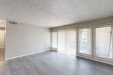 Located at 4001 Lakemont Dr in College Park, Georgia, this single-floor residence offers two bedrooms and two bathrooms within a well-organized layout. The spacious living room serves as the heart of the home, featuring durable wood-style flooring, textured ceilings, and white vertical-paneled accent walls. Large sliding glass doors and flanking windows flood the space with natural light and provide views of the outdoors, while vertical blinds offer privacy control. A bold black front door adds a distinctive architectural touch to the entry.

The kitchen is outfitted with white cabinetry, dark countertops, a black electric range with overhead ventilation, and matching wood-style flooring, providing a clean and functional cooking space. A hallway connects the main living areas to the private quarters.

Both bedrooms feature plush carpeting, neutral-toned walls, textured ceilings, and windows that bring in natural light. The generously sized primary bedroom includes a walk-in closet with built-in shelving and hanging rods on both sides, leading directly to a private bathroom. The bathrooms include a full bathtub and vanity with cabinet storage. The overall color palette of soft grays and whites creates a clean, neutral ambiance throughout the home.