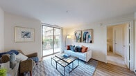 This thoughtfully designed 2-bedroom, 2-bathroom residence offers a comfortable and efficient single-floor layout. The bright living room serves as the heart of the home, featuring wood-style flooring, clean white walls, and a large sliding glass door that opens to a private balcony with lush outdoor views — flooding the space with natural light. The adjoining kitchen is equipped with warm wood cabinetry, white appliances including an electric range and built-in microwave, light countertops, and wood-style flooring that connects seamlessly to the dining area. The primary bedroom is a spacious, carpeted retreat with a large window that frames greenery outside, providing a calm and restful atmosphere. The second bedroom is equally cozy, with plush carpet and natural light from a dedicated window. The two bathrooms are finished with tile flooring and neutral tones; one features a walk-in shower, while the other offers a full shower-tub combination — both with clean white fixtures and tasteful detailing. Throughout the residence, a neutral color palette and consistent finishes create a cohesive, inviting ambiance that is both practical and comfortable.