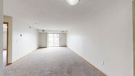 Located at 1119 41st St NW in Rochester, Minnesota, this single-floor, one-bedroom, one-bathroom unit offers a practical and efficient layout. The living room is a generous, open space featuring neutral carpet, a textured ceiling, and a sliding glass door that opens to a balcony, allowing natural light to fill the room and providing outdoor views. The kitchen is positioned adjacent to the living area and features oak cabinetry, a breakfast bar peninsula, tile flooring, and white appliances including a refrigerator and range with overhead ventilation. A functional layout connects the kitchen seamlessly to the rest of the unit. The bedroom is a well-proportioned, carpeted room with a window that brings in natural light and includes a full-width closet with bi-fold doors and wire shelving for organized storage. The bathroom is finished with large-format tile flooring, an oak vanity with a white countertop, and clean, neutral walls. Consistent wood baseboard trim throughout the unit ties the spaces together with a cohesive look. The overall ambiance is clean, understated, and move-in ready, offering a straightforward and comfortable living environment in a residential Rochester neighborhood.