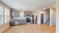 Located at 800 E Long Street in Columbus, Ohio, this well-designed two-story residence offers 1 bedroom and 2 bathrooms across two thoughtfully laid-out floors. The main level features an open-concept kitchen and living area bathed in natural light from large windows. The kitchen is appointed with grey shaker-style cabinetry, granite countertops, a subway tile backsplash, and a full suite of stainless steel appliances, including a refrigerator, range, microwave, and dishwasher. Durable light-toned hardwood-style flooring flows throughout the main level, complementing the clean, neutral palette. A stylish barn door adds a modern architectural touch to the hallway. The upper level hosts the private bedroom, which features plush carpeting, a bank of windows that invite natural light, and direct access to a spacious walk-in closet outfitted with wire shelving for ample storage. Both bathrooms are finished with granite-topped grey vanities and light tile flooring, maintaining a consistent modern aesthetic. Additional carpeted rooms on the upper level provide flexible living or storage space. The two-story layout, contemporary finishes, and functional design make this residence a refined and practical offering in Columbus.