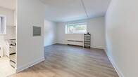 Located at 1600 Bathurst Street in Toronto's Forest Hill neighbourhood, this 2-bedroom, 1-bathroom unit offers a well-organized, single-floor layout with a clean and modern aesthetic. Throughout the unit, light-toned hardwood-style flooring creates a warm, cohesive look that ties each room together seamlessly.

The main living area is spacious and bright, featuring white walls, a baseboard heating unit, and a window that brings in natural light and a view of the surrounding greenery. A practical electrical panel is accessible from this room, adding functional convenience.

The kitchen is efficiently designed with white upper cabinetry, a marble-style backsplash, a dark countertop pass-through, and stainless steel appliances including a refrigerator and stove. Light tile flooring and recessed track lighting above give the kitchen a crisp, clean finish. A window at the far end allows for natural ventilation and light.

Both bedrooms are well-proportioned, featuring the same light hardwood flooring, white walls, and individual windows with baseboard heaters beneath them. The primary bedroom offers a comfortable footprint, while the second bedroom provides a cozy and versatile space. Dark-paneled interior doors add a subtle contrast to the unit's otherwise light palette.

The bathroom is finished with classic white subway tile surrounding a full soaker tub and shower combination, complemented by a small window for natural light — clean, timeless, and functional.