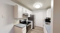 Located at 70002 N Colton St in Spokane, WA, this single-floor unit offers a thoughtfully designed layout with consistent, updated finishes throughout. Wood-look flooring runs continuously across the space, contributing to a cohesive and clean aesthetic, while textured ceilings add visual character to each room.

The living area is generously sized, providing ample room for seating and relaxation. A large sliding glass door floods the space with natural light and opens directly to an outdoor patio, creating a seamless connection to the exterior. A dedicated dining area sits adjacent, offering a practical space for meals.

The kitchen features white shaker-style cabinetry, gray countertops, a tile backsplash, and stainless steel appliances, including an electric range and refrigerator. A closet pantry provides additional storage.

A wide hallway connects the living spaces to the bedrooms, which are well-proportioned and include ample closet space. One bedroom benefits from a window with natural light, while the primary bedroom offers a generous footprint. The bathroom includes a white vanity with a gray countertop, overhead lighting, and a shower-tub combination. The overall ambiance is clean, neutral, and move-in ready.