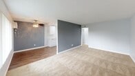 Located at 601–635 N Chippewa Ave in Anaheim, California, this single-story unit offers a well-organized layout with distinct living, dining, kitchen, and sleeping areas. The living room is generously sized, featuring neutral carpeting, soft grey walls, and a large window with vertical blinds that allows abundant natural light to fill the space. A ceiling fan adds both function and comfort. The open layout connects the living area to the kitchen and dining zone, creating a cohesive flow throughout the main living spaces. The kitchen is equipped with white cabinetry, a gas range, a dishwasher, and a stainless steel sink. Recessed lighting illuminates the workspace, while hardwood-style flooring adds a clean, contemporary touch. A window overlooking the exterior and a wall-mounted air conditioning unit provide ventilation and comfort. The bedrooms are carpeted and painted in calming grey tones, each featuring windows with vertical blinds that allow natural light while maintaining privacy. The bathroom is finished with a white vanity featuring a quartz-style countertop, a large mirror with vanity lighting, a full shower-tub combination, and hardwood-style flooring. Clean white fixtures and brushed nickel hardware complete the polished look of this functional and move-in-ready unit.