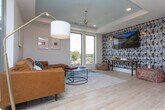 Located at 5039 W Broad St in Sugar Hill, GA, this single-floor space showcases a contemporary design with thoughtful architectural details throughout. The open-concept layout is anchored by light hardwood flooring that flows seamlessly from room to room, creating a cohesive and welcoming atmosphere.

The kitchen is a standout feature, boasting a bold navy blue island with shiplap paneling and white quartz countertops, complemented by warm wood cabinetry, open floating shelves, and a navy accent wall with textured tile backsplash. Pendant lighting with gold fixtures adds a refined touch, while a built-in beverage cooler and farmhouse sink elevate the space's functionality.

The living area is bright and airy, featuring a tray ceiling painted in a muted blue-gray tone and adorned with a striking sputnik chandelier. Large windows and direct access to an outdoor balcony flood the room with natural light and offer open views of the surrounding Sugar Hill landscape. The entry area makes a bold statement with a floor-to-ceiling textured navy patterned accent wall, tray ceiling with gold multi-bulb light fixtures, and a glass door leading to the balcony. Throughout the space, the interplay of bold color accents, modern fixtures, and abundant natural light creates a vibrant yet sophisticated environment.