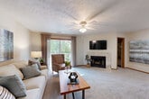 Located in La Vista, Nebraska, this well-appointed one-bedroom, one-bathroom unit offers a thoughtfully designed layout across a single floor. The inviting living room serves as the heart of the home, featuring a tile-surround fireplace, plush carpeting, a ceiling fan, and a sliding glass door that opens to a private balcony with lush outdoor views, flooding the space with natural light. The open flow leads into a dedicated dining area, comfortably sized for a full dining table and accented by tasteful wall art, making it ideal for everyday meals or entertaining guests. The galley-style kitchen is efficiently arranged with warm oak cabinetry, dark granite-style countertops, a double sink, and white appliances including a range and refrigerator, all set atop easy-care wood-look flooring. The spacious primary bedroom offers a relaxing retreat with soft carpeting, a ceiling fan, a natural light-filled window with drape treatments, and generous closet storage. The full bathroom includes a tub-shower combination with clean white finishes and wood-look flooring. Two closets provide ample storage throughout the unit, while textured ceilings and neutral tones lend a warm, cohesive ambiance to the entire space.