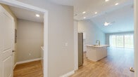 This single-floor residence offers a thoughtfully designed layout with a clean, contemporary aesthetic throughout. The kitchen serves as a central highlight, showcasing white shaker-style cabinetry extending to the ceiling, light quartz countertops, and a full suite of stainless steel appliances including a refrigerator, electric range, built-in microwave, and dishwasher. A central island with an undermount sink and gold-toned faucet provides additional prep space and a natural gathering point. Light-toned hardwood-style flooring runs throughout the kitchen and main living areas, complementing the neutral wall palette.

The kitchen opens toward the living area beneath vaulted ceilings fitted with recessed lighting and a ceiling fan, creating an airy, open atmosphere. A dedicated laundry area houses a full-size Whirlpool washer and dryer. The bedrooms feature plush carpeting, neutral walls, and windows with blinds that bring in natural light. The bathroom includes a full-size soaking tub and shower combination with clean white surround and chrome fixtures. Overall, the space conveys a fresh, move-in-ready feel with practical, well-maintained finishes throughout.