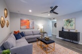 This thoughtfully designed single-floor residence in Cypress, TX offers a cohesive blend of modern aesthetics and functional living spaces throughout. The main living area features wood-look flooring, recessed lighting, a ceiling fan, and contemporary décor, creating a warm and inviting atmosphere. A separate lounge area with vaulted ceilings and a large sectional sofa provides additional space for relaxation and entertainment.

The dining area is elegantly appointed, with room for a round dining table and chairs, complemented by stylish wall art and accent lighting. The galley-style kitchen is well-equipped with gray shaker cabinetry, quartz countertops, a white subway tile backsplash, stainless steel appliances, and wood-look flooring, with convenient access to a pantry with built-in shelving.

The primary bedroom offers plush carpeting and a serene, neutral palette, while a secondary bedroom provides a vibrant, youthful space with carpet flooring and a dedicated study area. The bathrooms feature gray vanity cabinetry, white countertops, wood-look flooring, and a tub-shower combination. A spacious walk-in closet with wire shelving adds practical storage. The home's neutral tones and modern finishes create a clean, contemporary ambiance throughout.