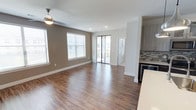 Located in Frisco, this well-appointed single-floor unit offers a thoughtfully designed open-concept layout that seamlessly connects the living area and kitchen. Rich hardwood-style flooring runs throughout the main living space, complemented by warm taupe walls and crisp white trim. The living area is bathed in natural light from multiple windows with blinds and a sliding glass door that opens to a private balcony, offering pleasant outdoor views. A ceiling fan adds comfort to the space.

The gourmet kitchen is a standout feature, showcasing two-tone cabinetry—light upper cabinets and dark lower cabinets—paired with a striking mosaic tile backsplash. A large island with a white quartz countertop and an undermount sink with a commercial-style faucet serves as the focal point, while stainless steel appliances including a refrigerator, range, and microwave complete the space. A built-in wine cooler adds an upscale touch.

Two bathrooms offer distinct experiences. The primary bathroom features a granite-topped vanity, a soaking tub with tile surround, a walk-in closet, and hardwood-style flooring. The secondary bathroom includes a vanity with stone countertop and a glass-enclosed walk-in shower with tile walls. Both bathrooms are finished with clean, contemporary fixtures throughout.