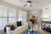 Located in Baton Rouge, LA, this well-designed 2-bedroom, 2-bathroom single-story home offers a thoughtfully planned layout across a comfortable footprint. The open-concept living area is bright and welcoming, featuring wood-style flooring, crown molding, and a ceiling fan overhead. Large windows dressed with white blinds flood the space with natural light, creating an airy atmosphere. The living area flows seamlessly into the dining room, which is anchored by a pendant light fixture and accented with crown molding, and connects directly to the kitchen. The kitchen is equipped with warm wood cabinetry, granite-style countertops, black appliances including a refrigerator, range, microwave, and dishwasher, and a pass-through window that maintains visual connectivity with the main living space. A hallway with wood-style flooring leads to both bedrooms. The primary bedroom is generously sized, featuring a ceiling fan, a large window with natural views, and direct access to a walk-in closet with wraparound wire shelving. The second bedroom is equally comfortable with its own ceiling fan and natural light. Both bathrooms include wood cabinetry and tub-shower combinations. Additional features include an in-unit laundry area, completing this well-appointed home.